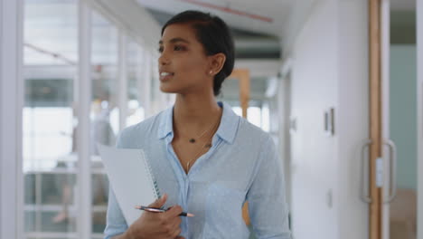 young mixed race business woman walking through office smiling holding documents enjoying successful career in corporate workplace 4k
