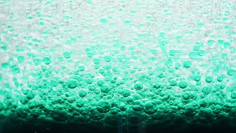 macro shot of dark blue bubbles setting on ground of water with a bright yellow background