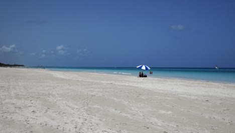 Fantastischer-Strand-Von-Varadero-An-Einem-Sonnigen-Tag,-Feiner-Weißer-Sand-Und-Türkisfarbenes-Und-Grünes-Karibisches-Meer,-Rechts-Ein-Blauer-Sonnenschirm,-Kuba