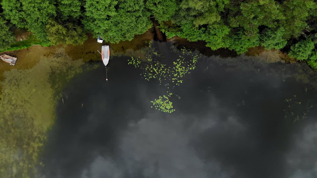 호숫가에 정박하고 폴란드 프라드존카(pradzonka)의 무성한 녹색 침엽수림 옆 잔잔한 물 위에 떠 있는 보트