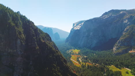 green sunny valley among the cliff rocks of yosemite national park, california, united states. aerial view at backdrop of clear skies.