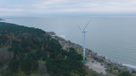 establishing aerial view of abandoned seaside fortification buildings at karosta northern forts on the beach of baltic sea in liepaja, overcast day, wind turbine, drone shot moving forward