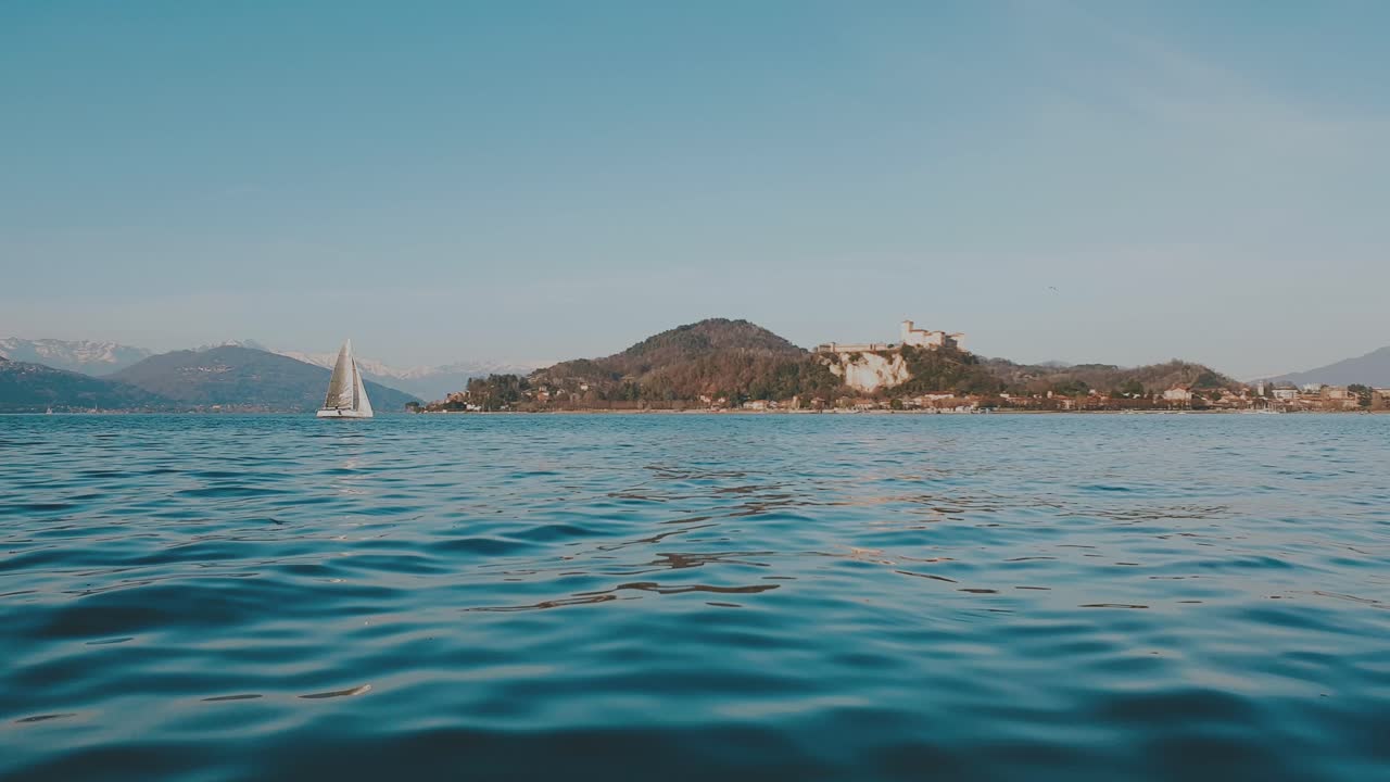 maggiore 호수에서 항해하는 작은 보트의 청록색 낮은 각도 표면 보기