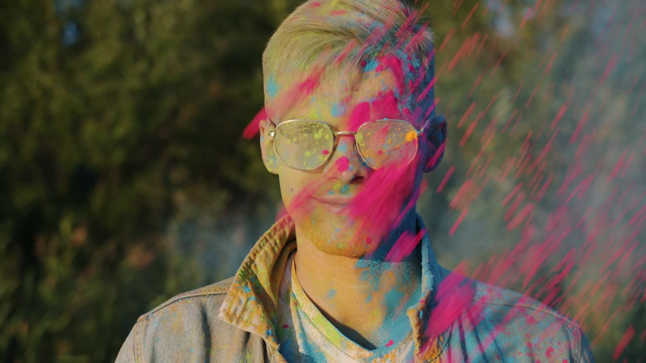 retrato en cámara lenta de un tipo emocionado sonriendo mientras sus amigos le tiran pintura en polvo divirtiéndose en el festival de holi