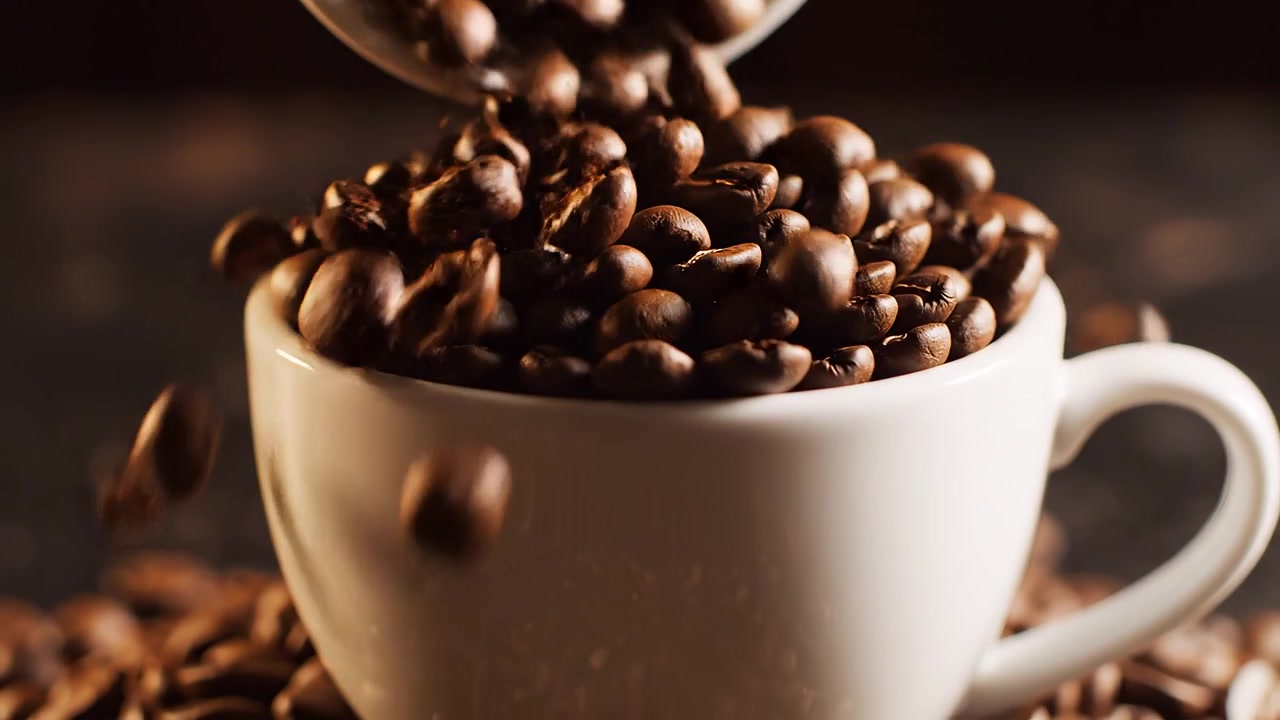 Kaffebønner som helles i hvit keramisk kopp på mørk bakgrunn