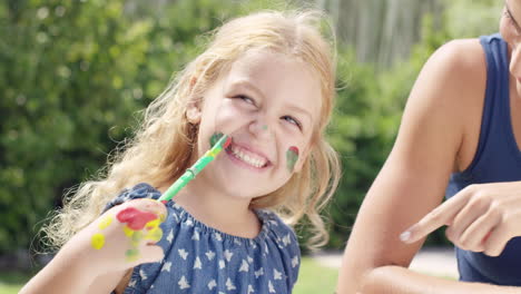 familia feliz con una niña pequeña pintando y haciendo un lío en el patio