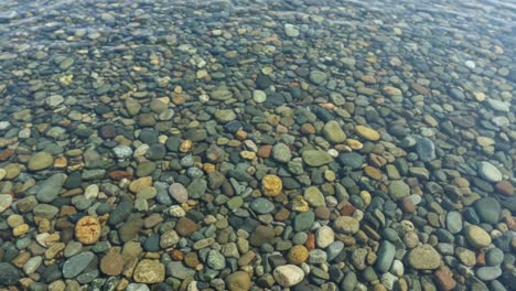 a serene view of colorful stones beneath crystal clear water, showcasing the beauty of nature's textures and patterns in a calm underwater scene
