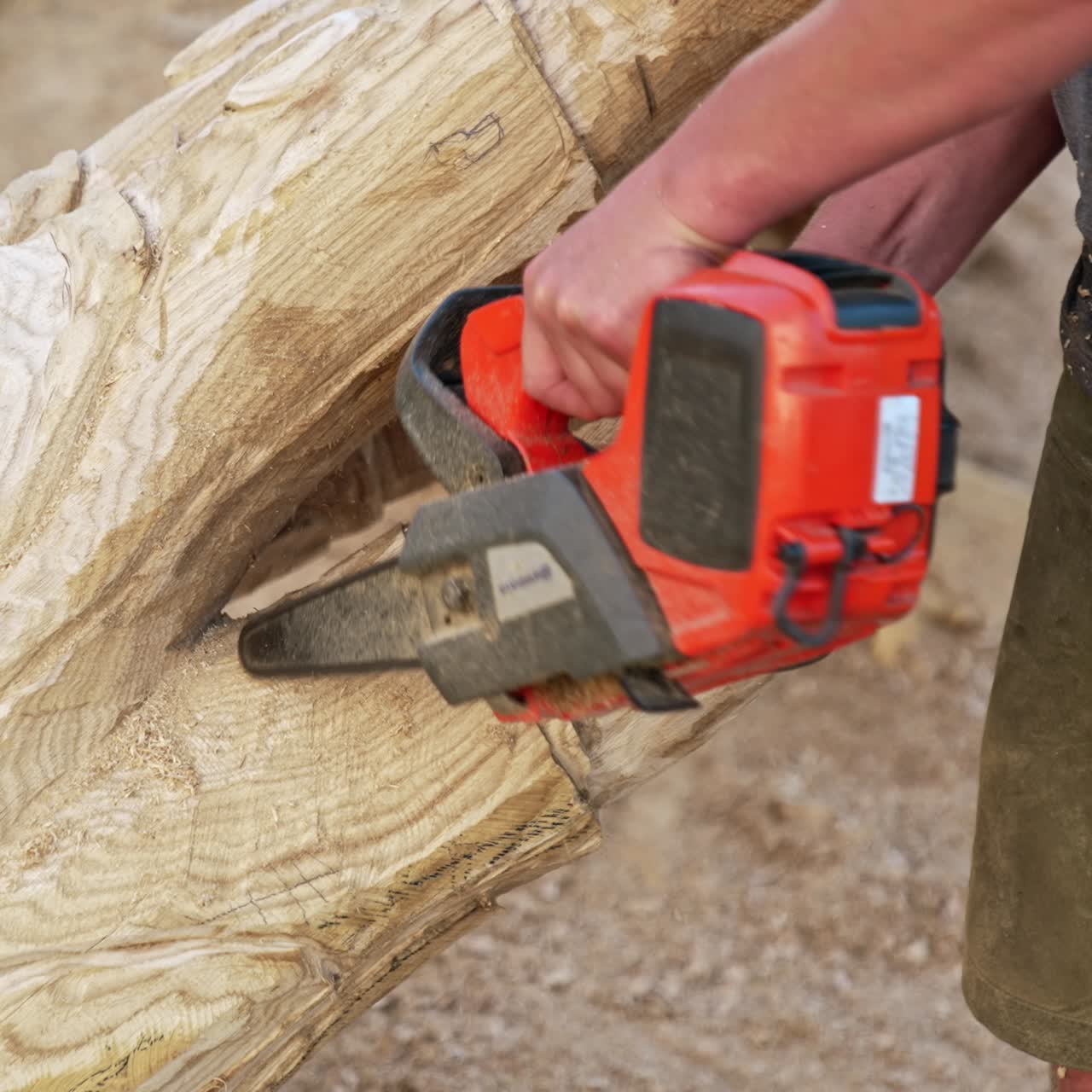 Unrecognized hands of a male artist working with a chain saw. Man making a wooden sculpture of a hand