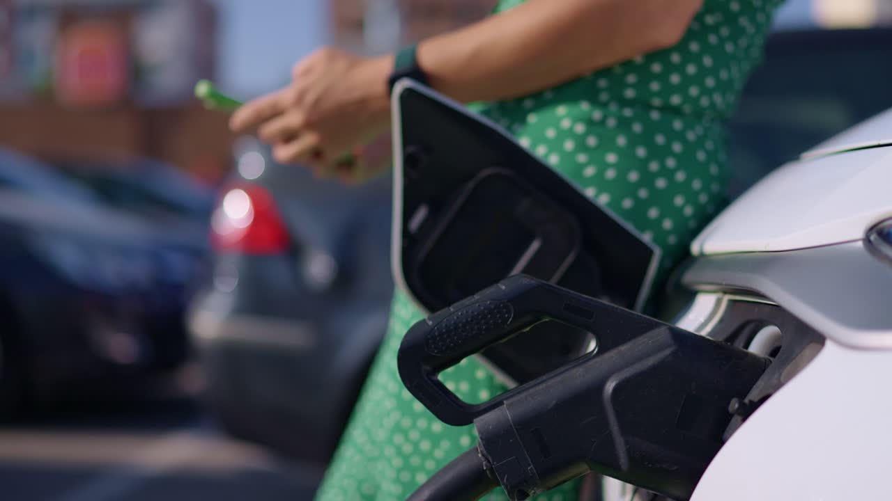Woman charging her electric car at a charging station