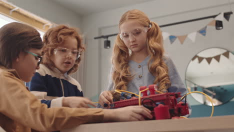 three classmates constructing robot during lesson