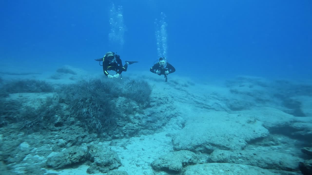 dos jóvenes buceando juguetonamente relajados bajo el agua con aletas