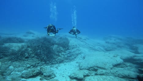 two young men scuba diving playfully relaxed underwater with fins