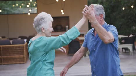 senior caucasian couple dancing and smiling in the garden