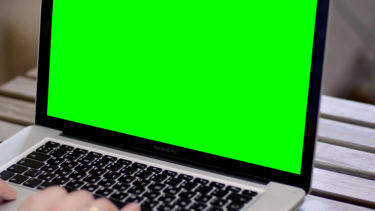 mano de un hombre trabajando en una computadora portátil escribiendo en el teclado. pantalla verde de cerca