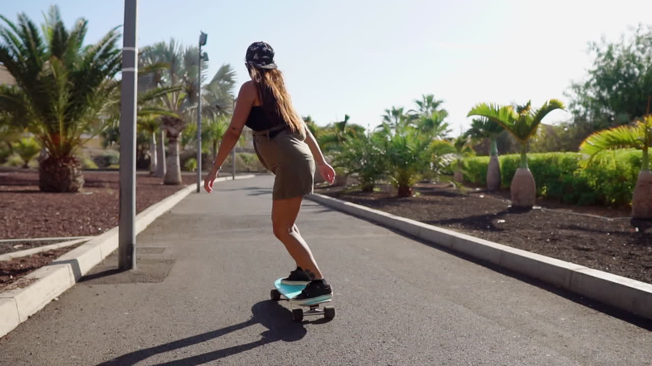 con palmeras y la playa a la vista, la cámara lenta ilustra la vista encantadora de una niña en su longboard