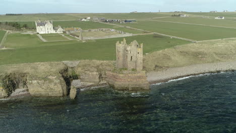 aerial shot backing away from keiss castle out towards the sea on a sunny day, caithness, scotland