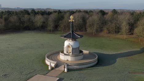 An-aerial-view-of-the-Peace-Pagoda-at-Willen-Lake-in-Milton-Keynes,-on-a-cold-winter-morning-with-the-sun-shining