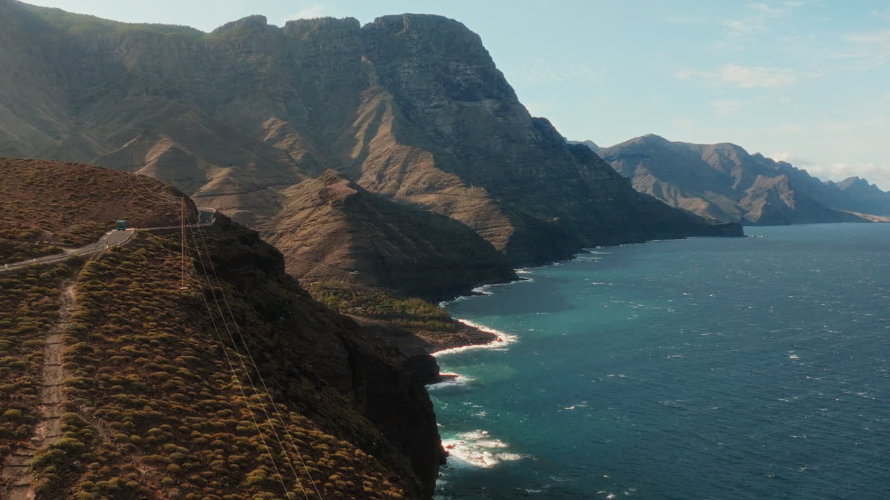 Drone flying over hill top capturing picturesque beauty of hills and sea during afternoon in Gran Canaria, Spain.