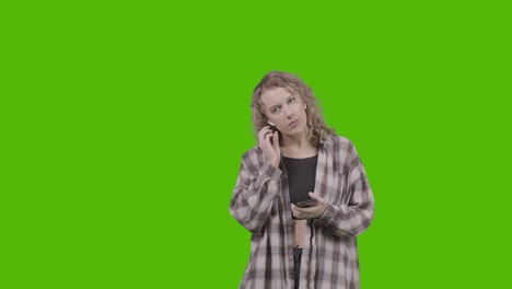 Studio-Shot-Of-Young-Woman-Listening-To-Music-On-Mobile-Phone-And-Dancing-Against-Green-Screen