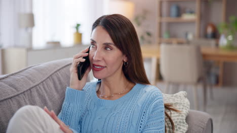 mujer hablando por teléfono mientras está sentada en un sofá