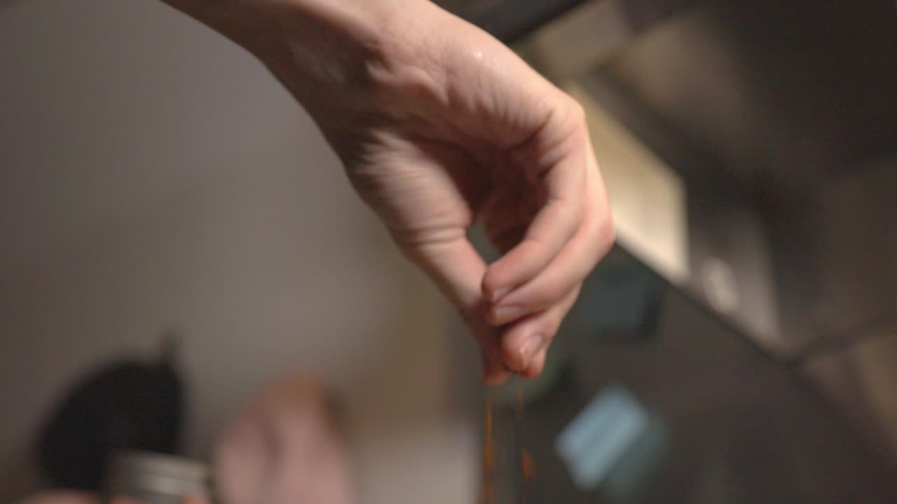 Mano che cosparge spezie per condire il cibo. - angolazione dal basso