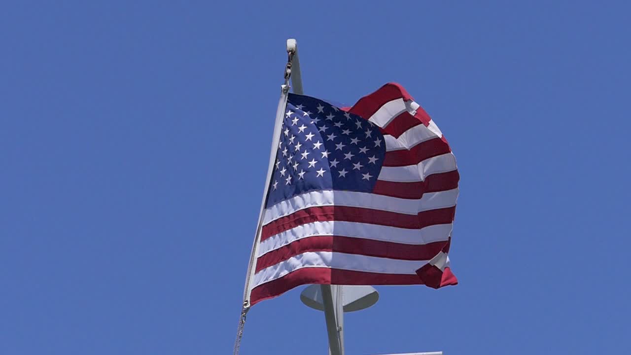 Ripresa al rallentatore di una bandiera americana con un cielo blu perfetto come sfondo