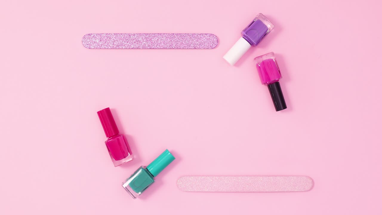 marco de espacio creativo de copia hecho de botellas de esmalte de uñas y archivos en fondo rosa brillante. stop motion