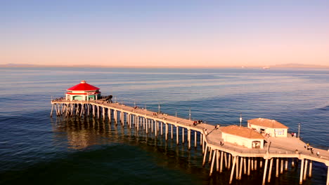 Huntington-Beach-Pier-aerial-4k-drone-flyover-with-dIner-and-bait-shops-visible,-Pacific-Ocean-at-sunrise,-early-morning,-wide,-smooth,-Catalina-Island-visible,-Southern-California