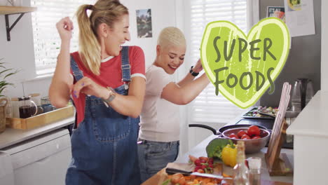 animation of super foods text over diverse female couple cooking at home