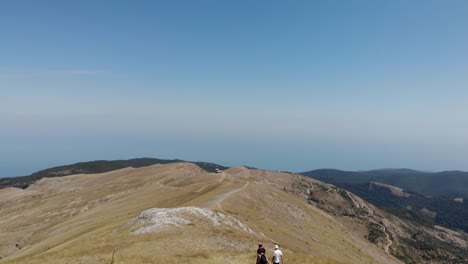 Antena:-Volando-Sobre-La-Montaña-Kissavos-En-La-Parte-Superior-De-Grecia-Revelando-Los-Hermosos-Paisajes,-Tiro-De-Día-De-Drones,-Cielo-Limpio-Y-Soleado,-Gente-De-Los-árboles-Caminando-Por-El-Sendero-De-La-Montaña