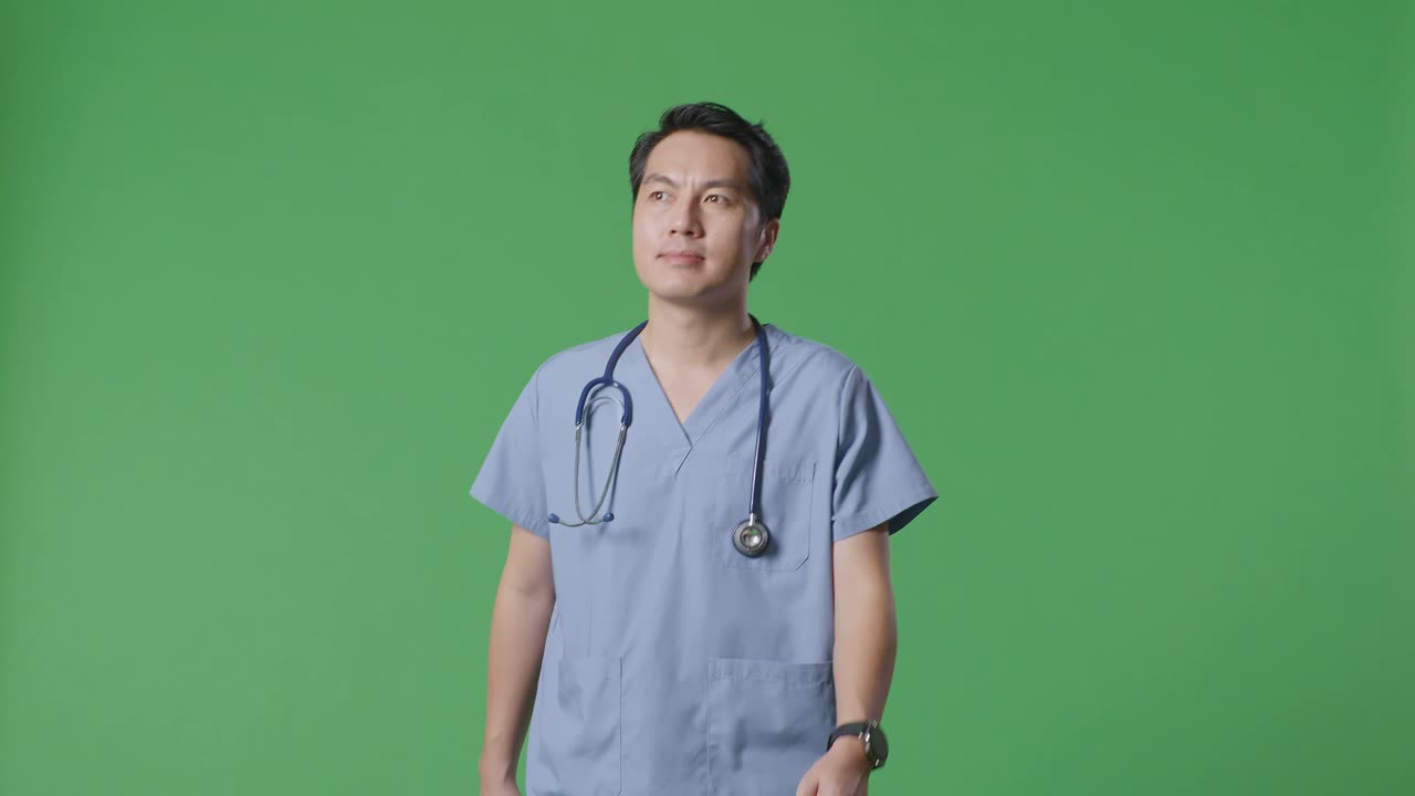 스테토스코프를 들고 있는 아시아 남성 의사 가 병원 의 초록색 스크린 배경 에서 돌아다니고 있다