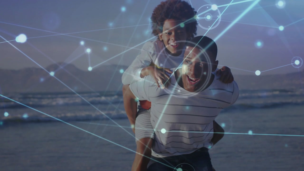 Man rising and walking carrying boy on back on shore, tech overlay animating over faces, bonding