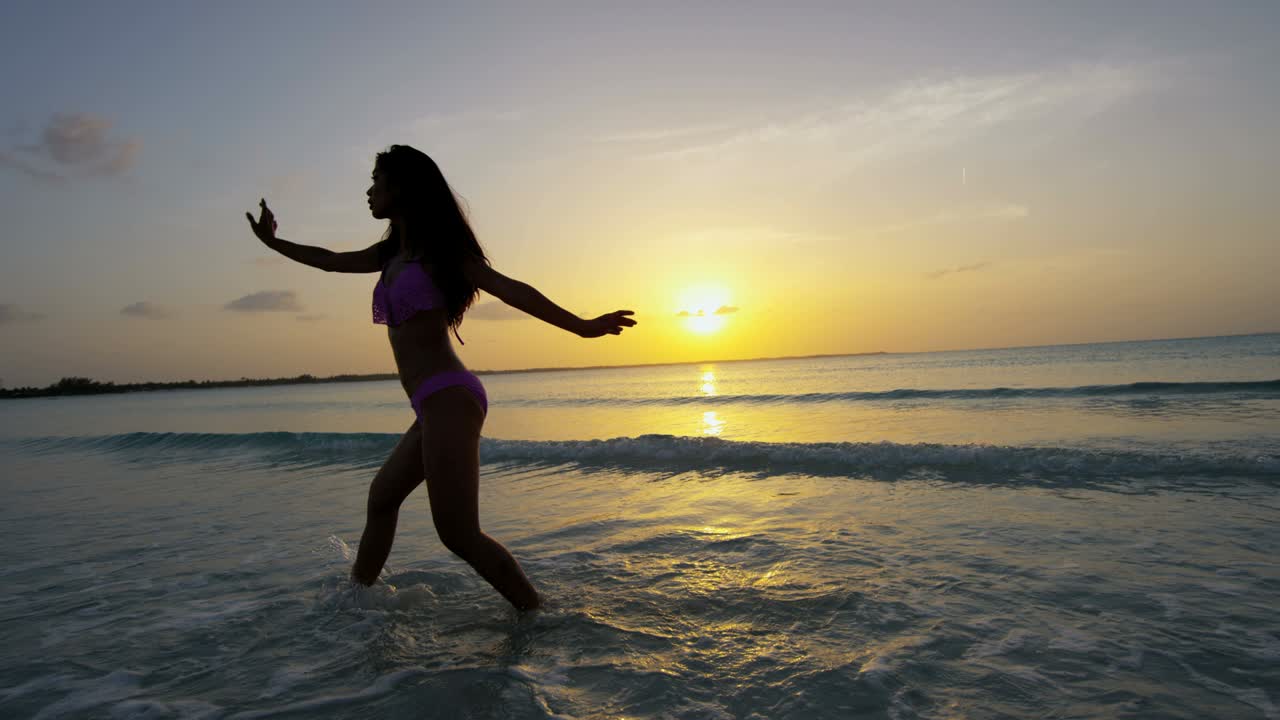 chica étnica descalza bailando despreocupada en una playa tropical