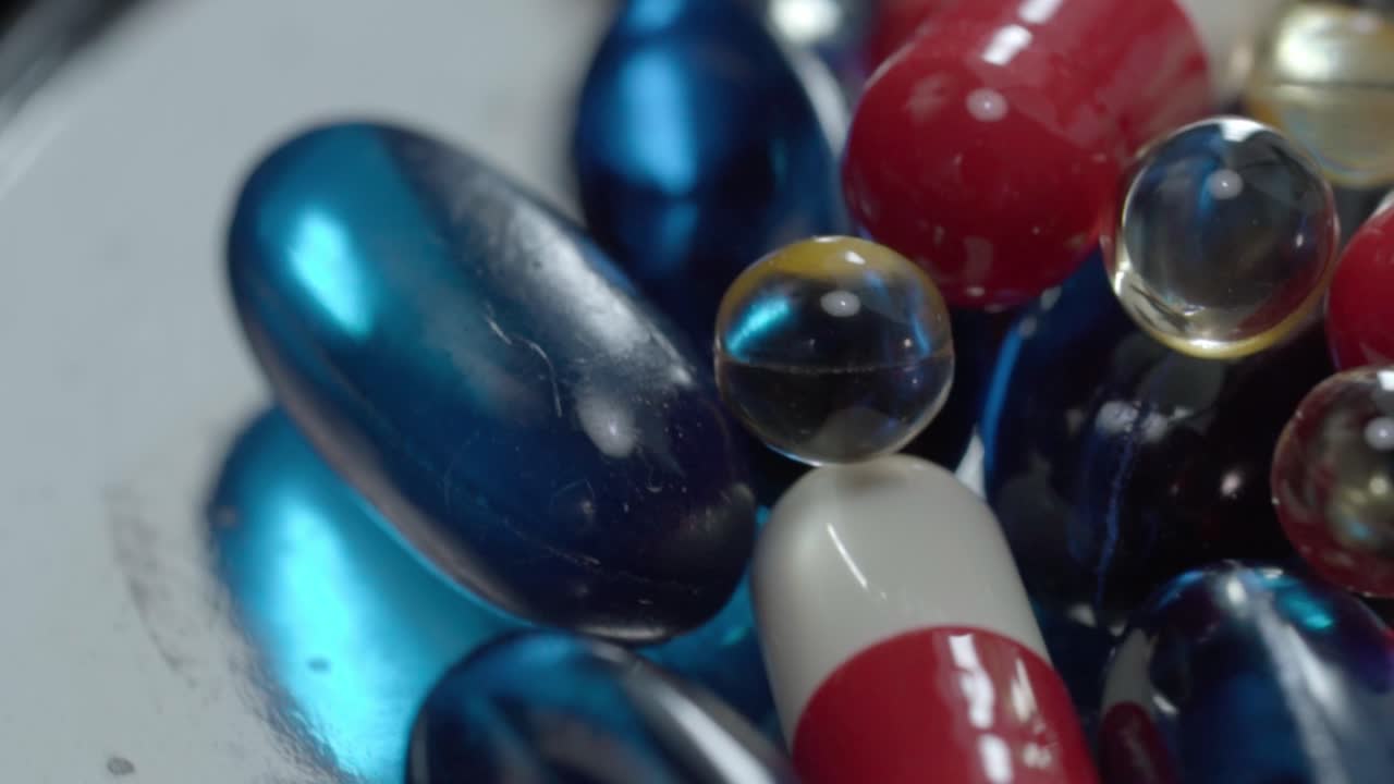 Macro shot of assorted red, white and blue capsules with transparent softgel pills, studio detail