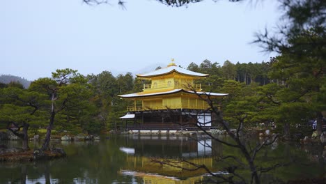 golden kinkakuji temple with snow on rooftop reflecting in pond