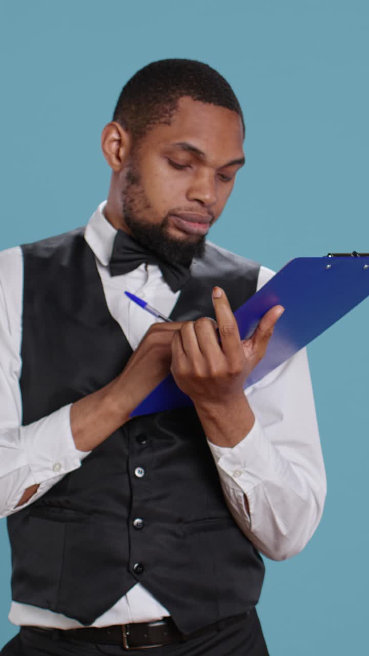 Professional Waiter Taking Notes on Clipboard and Thinking