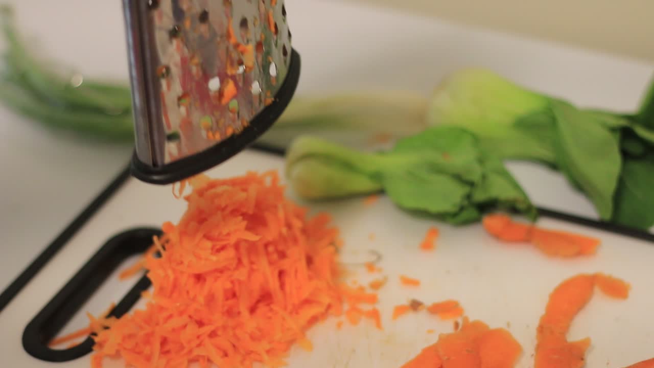 levantar el rastrillo para mostrar las zanahorias ralladas en una tabla de cortar