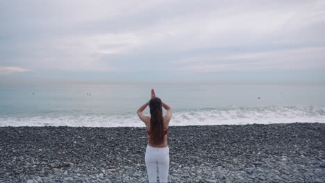 mujer practicando yoga en una playa de guijarros