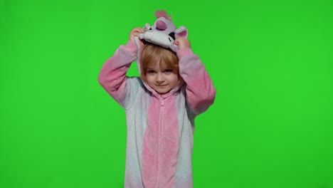 Little-blonde-child-girl-smiling,-putting-on-unicorn-costume-pajamas-on-chroma-key,-slow-motion