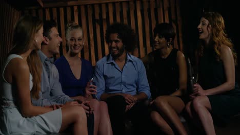 group of smiling friends interacting while having a glass of champagne