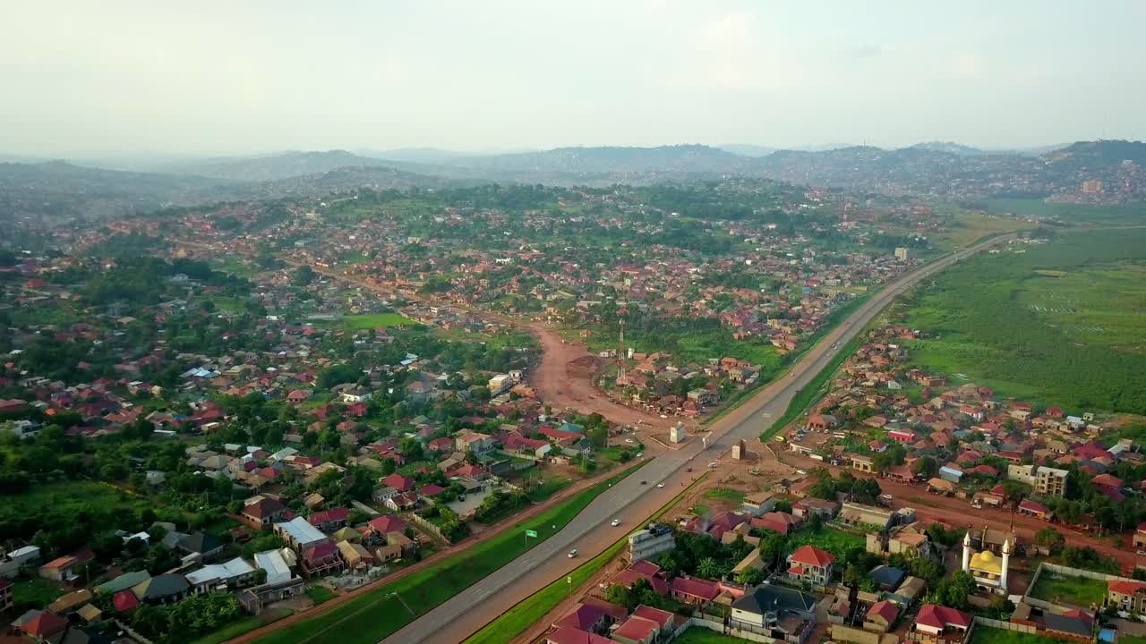 autopista kampala-entebbe, uganda, áfrica oriental - vehículos que viajan en la autopista junto a una comunidad residencial - fotografía aérea de un dron