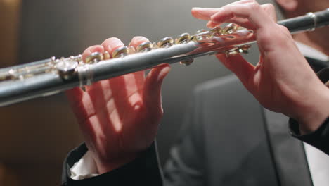 flute in hands of talented musician flutists is playing classic music in opera house or philharmonic hall