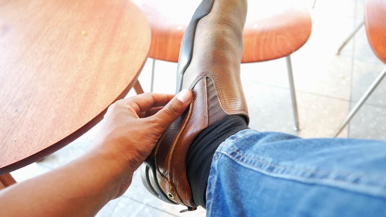 hombre ajustando un zapato de cuero marrón mientras está sentado