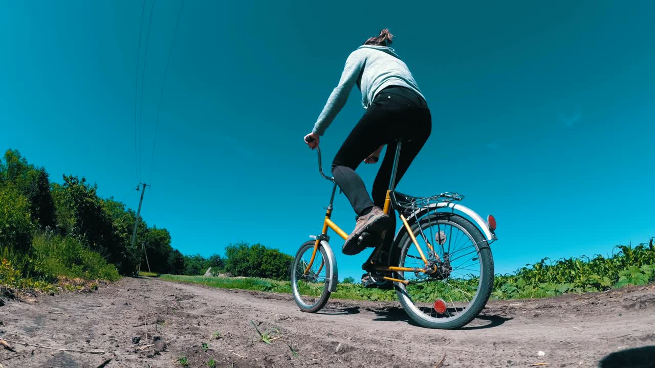 마을 의 시골 도로 를 따라 빈티지 자전거 를 타고 있는 젊은 여자