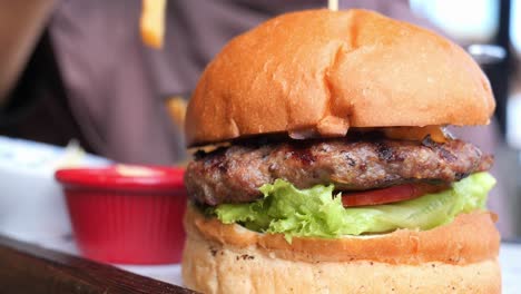 close up of a juicy beef burger with lettuce, tomato and a bun