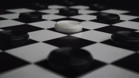 checkers white piece perfectly falling at the the center of a chessboard between black pieces (draughts)