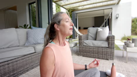 Mujer-Caucásica-Con-Pelo-Gris-Meditando-En-El-Patio.