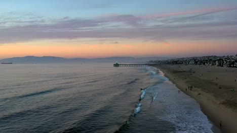 paisaje sereno en la playa de manhattan con turistas en la orilla al atardecer - toma aérea de drones