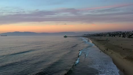 serene scenery at manhattan beach with tourists on the shore at sunset - aerial drone shot