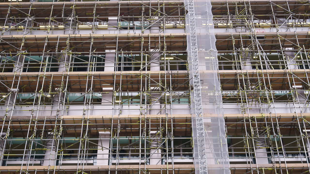 Close-up of a building facade covered in scaffolding and protective mesh during construction or renovation